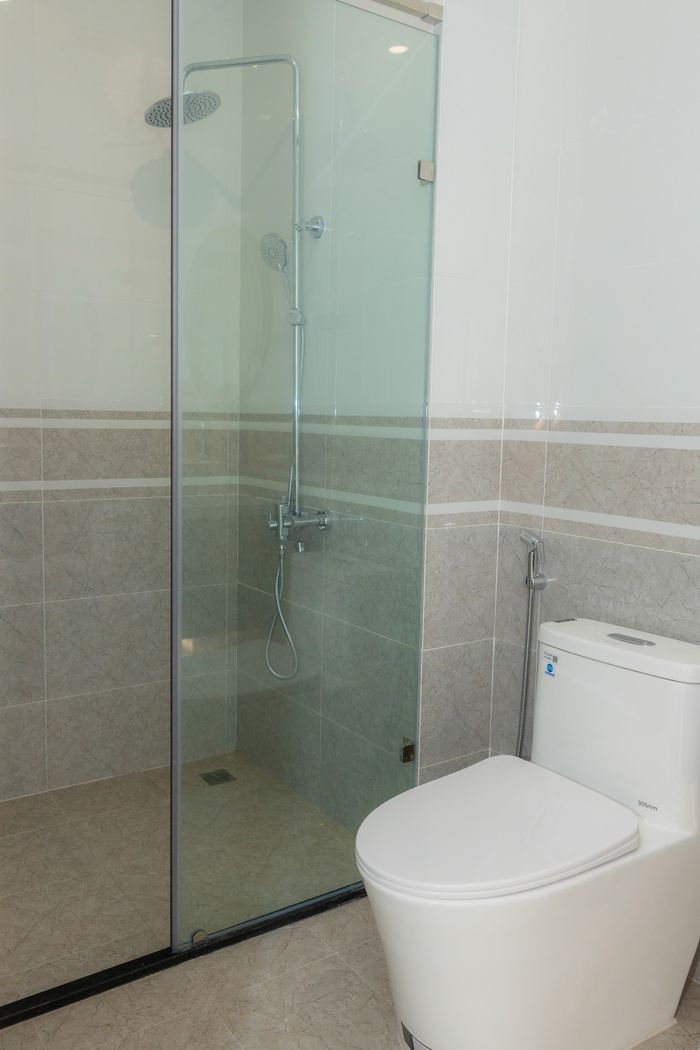A clean and spacious modern bathroom featuring a glass shower enclosure and toilet.