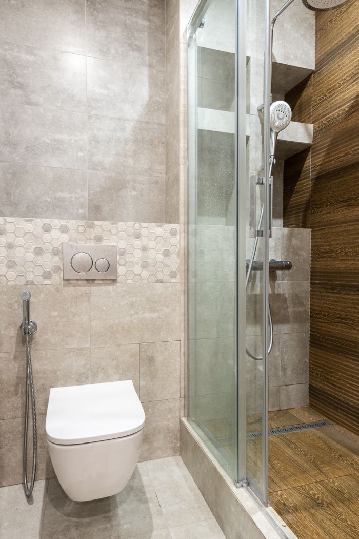 A sleek, modern bathroom featuring a shower stall and wall-mounted toilet.