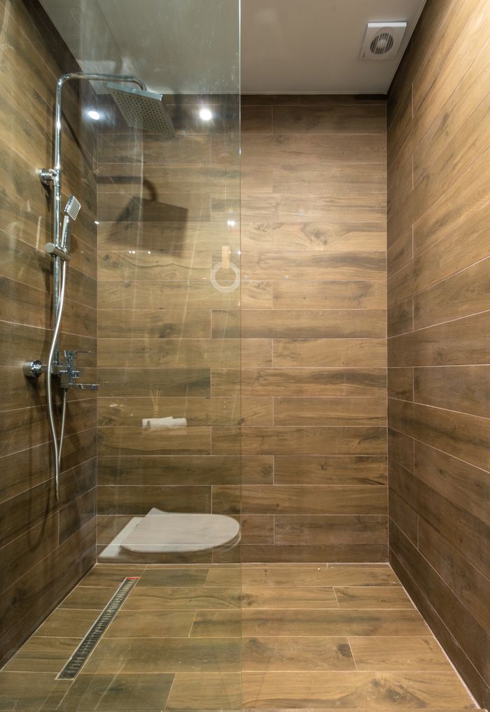 Elegant wooden-themed shower stall with clean glass partition in a modern bathroom setting.